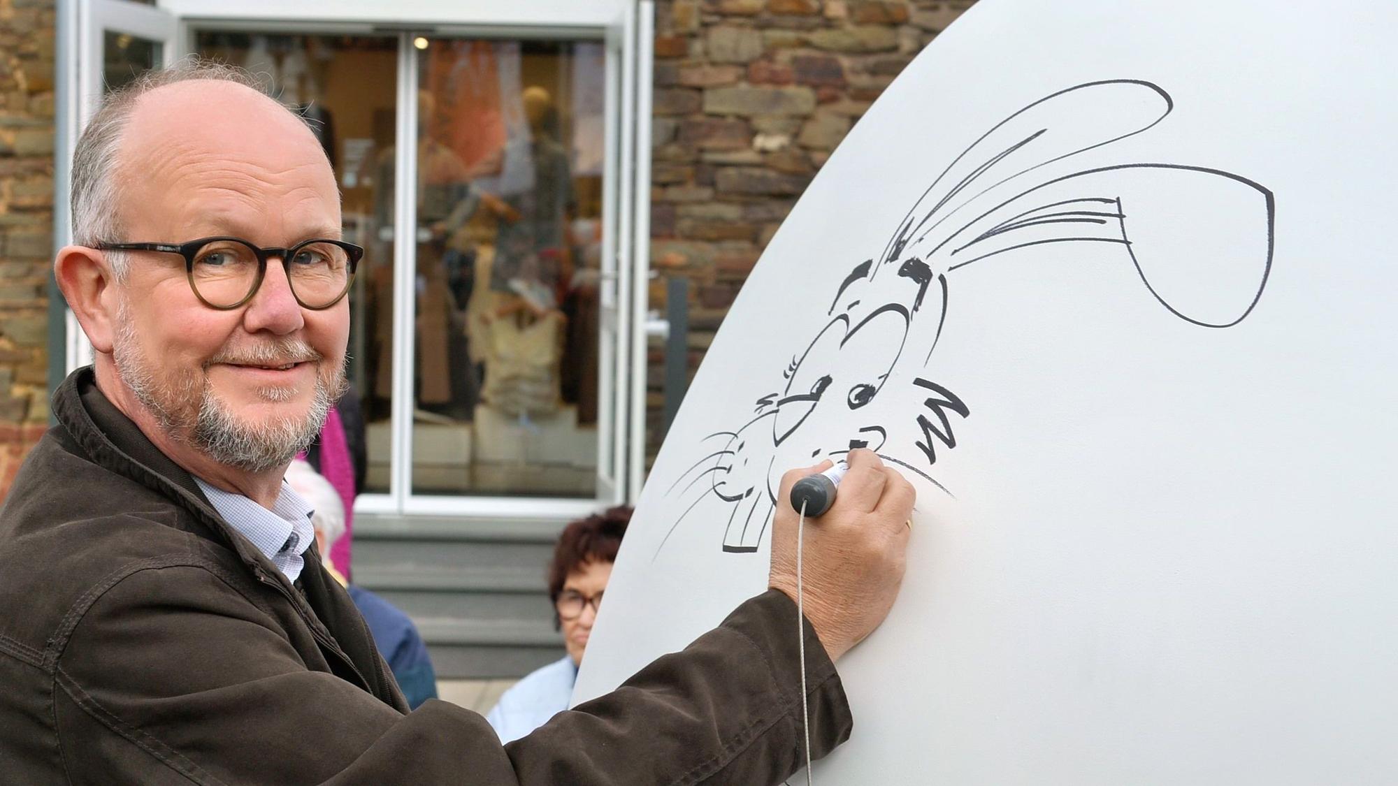 Das Bild zeigt Ralf Kramp, wie er mit einem Stift einen Hasen malt.