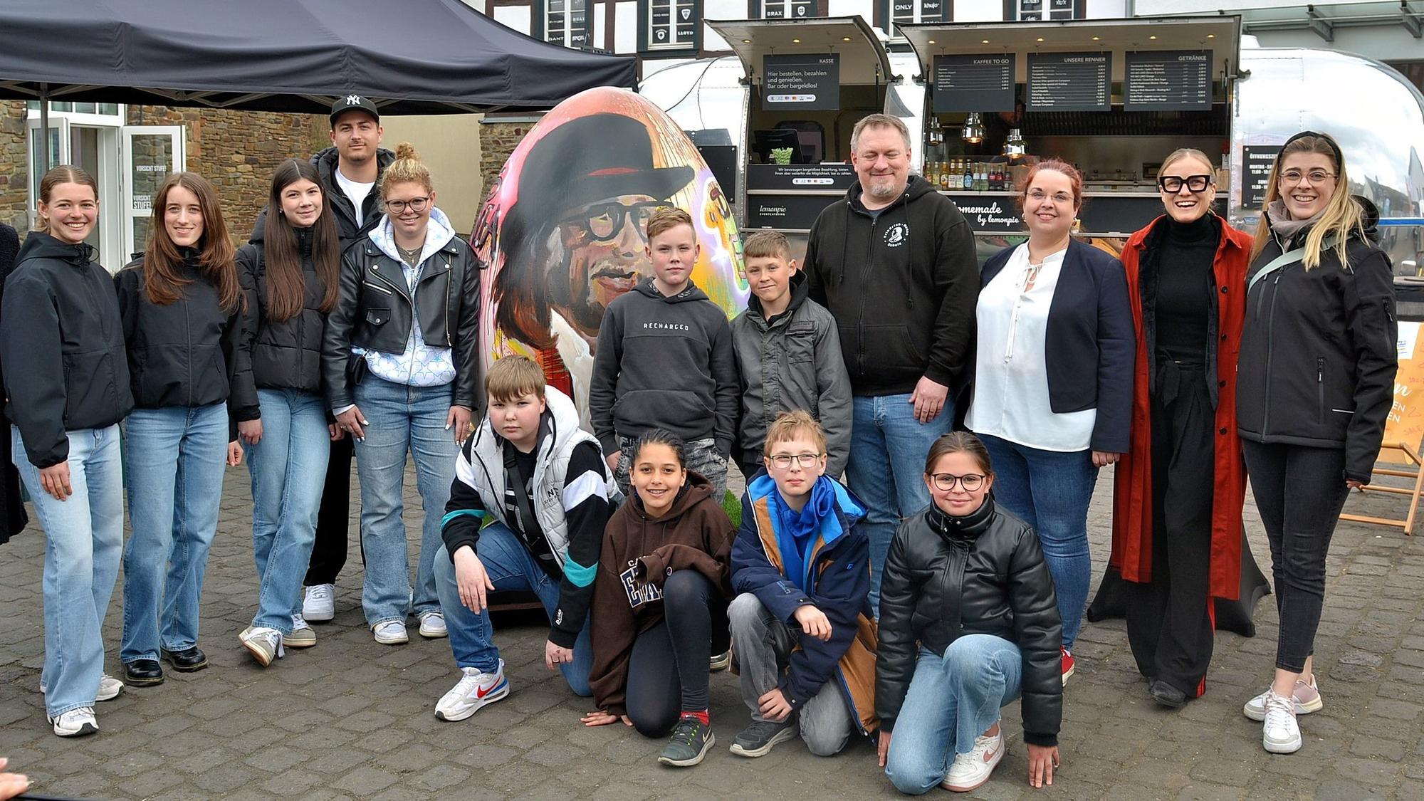 Schülerinnen und Schüler haben sich vor einem Kunst-Ei aufgestellt.