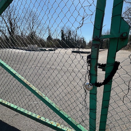 Auf dem Bild ist ein leergeräumtes Grundstück der Stadt durch eine Maschendrahtzaun zu sehen.