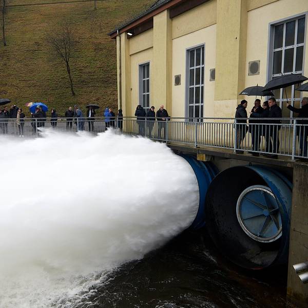 Zahlreiche Personen beobachten, wie eine gewaltige Wasserfontäne aus dem Grundablass der Rurtalsperre schießt.