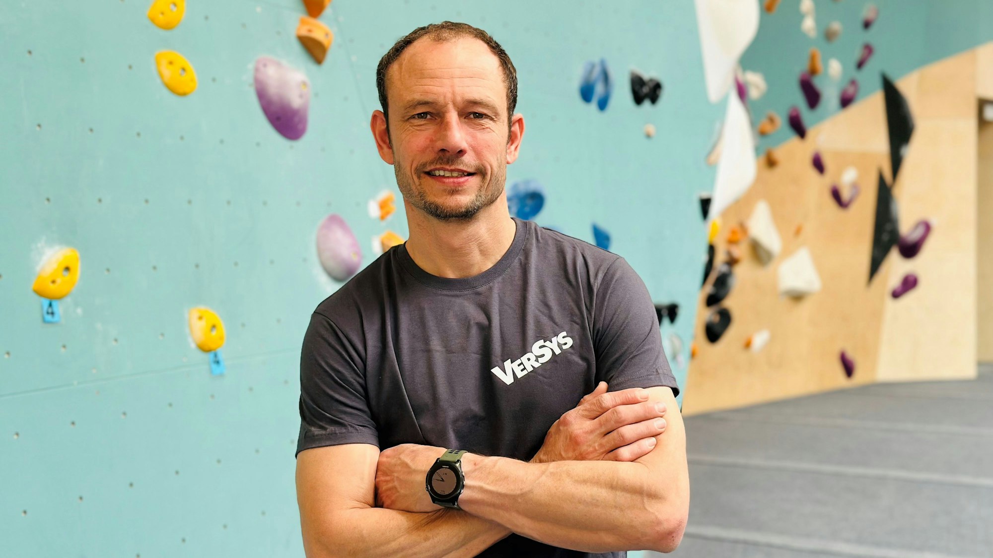 Ein Mann steht vor einer Kletterwand.