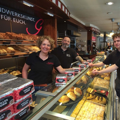 Zu sehen ist eine vierköpfige Bäckerfamilie in ihrem Cafe.