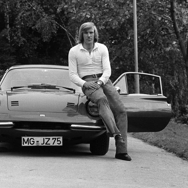 Das Bild zeigt Günther, den ersten Popstar des deutschen Fußballs, wie er lässig an der Motorhaube seines Sportwagens lehnt.