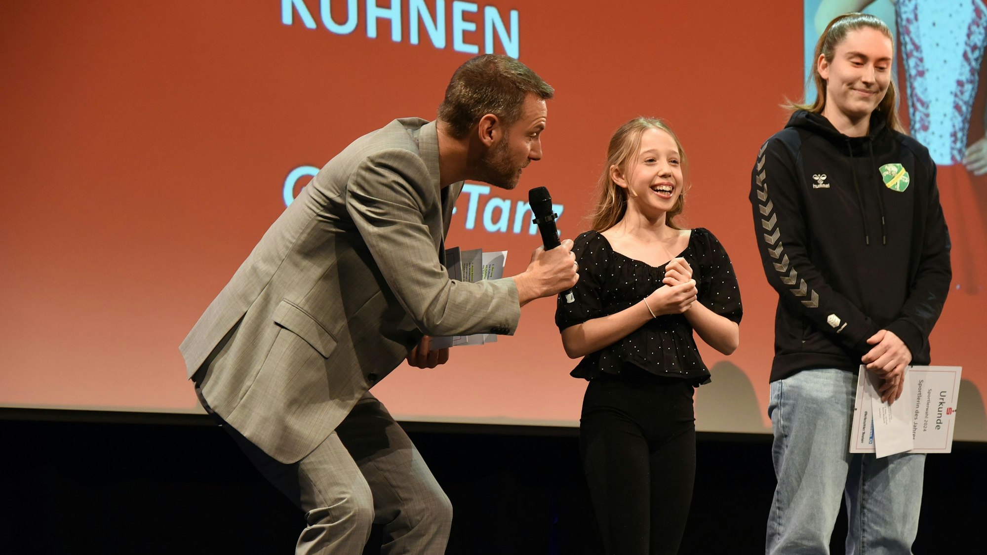 Zu sehen ist ein Moderator, der ein zwölfjähriges Mädchen interviewt.