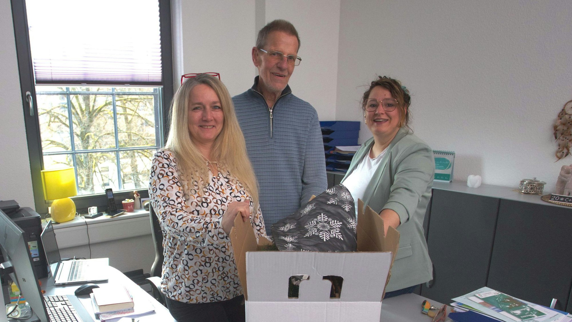 Zwei Frauen und ein Mann stehen zusammen in einem Büro.