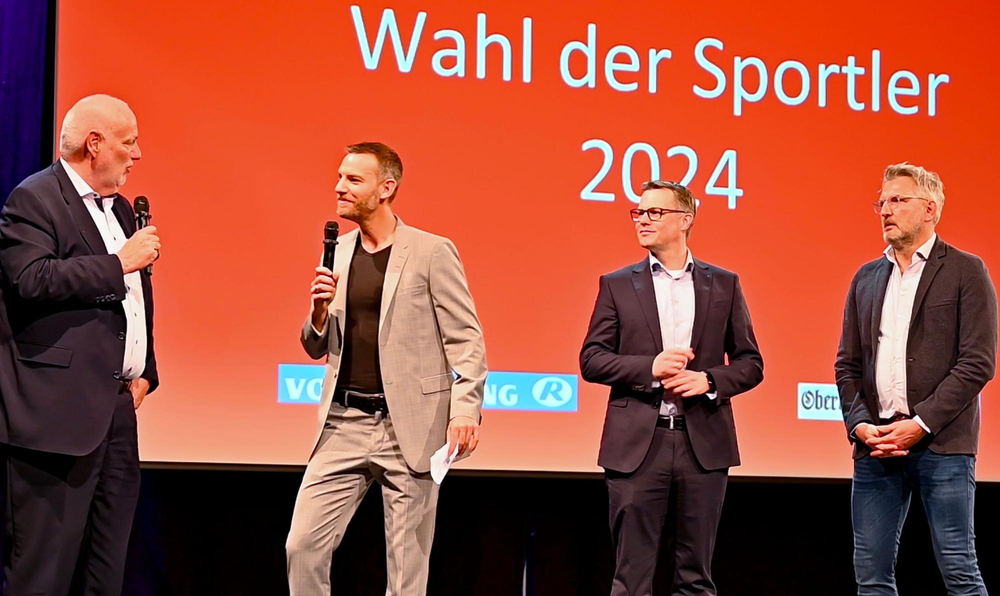 Blick auf vier Männer, die auf einer Bühne stehen.