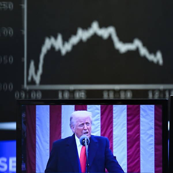 Hinter einem Fernsehmonitor, auf dem US-Präsident Donald Trump zu sehen ist, zeigt die Anzeigetafel mit der Dax-Kurve fallende Kurse