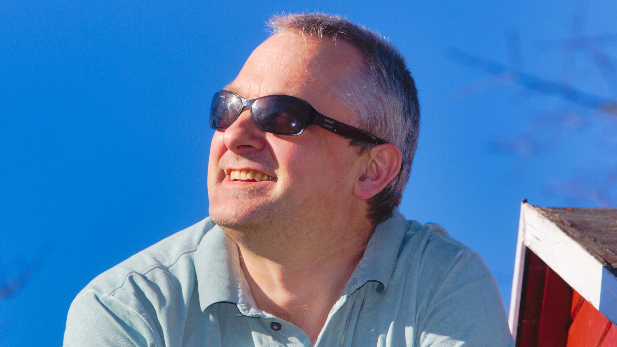 Porträt eines Mannes, der mit Sonnenbrille in die Sonne schaut.