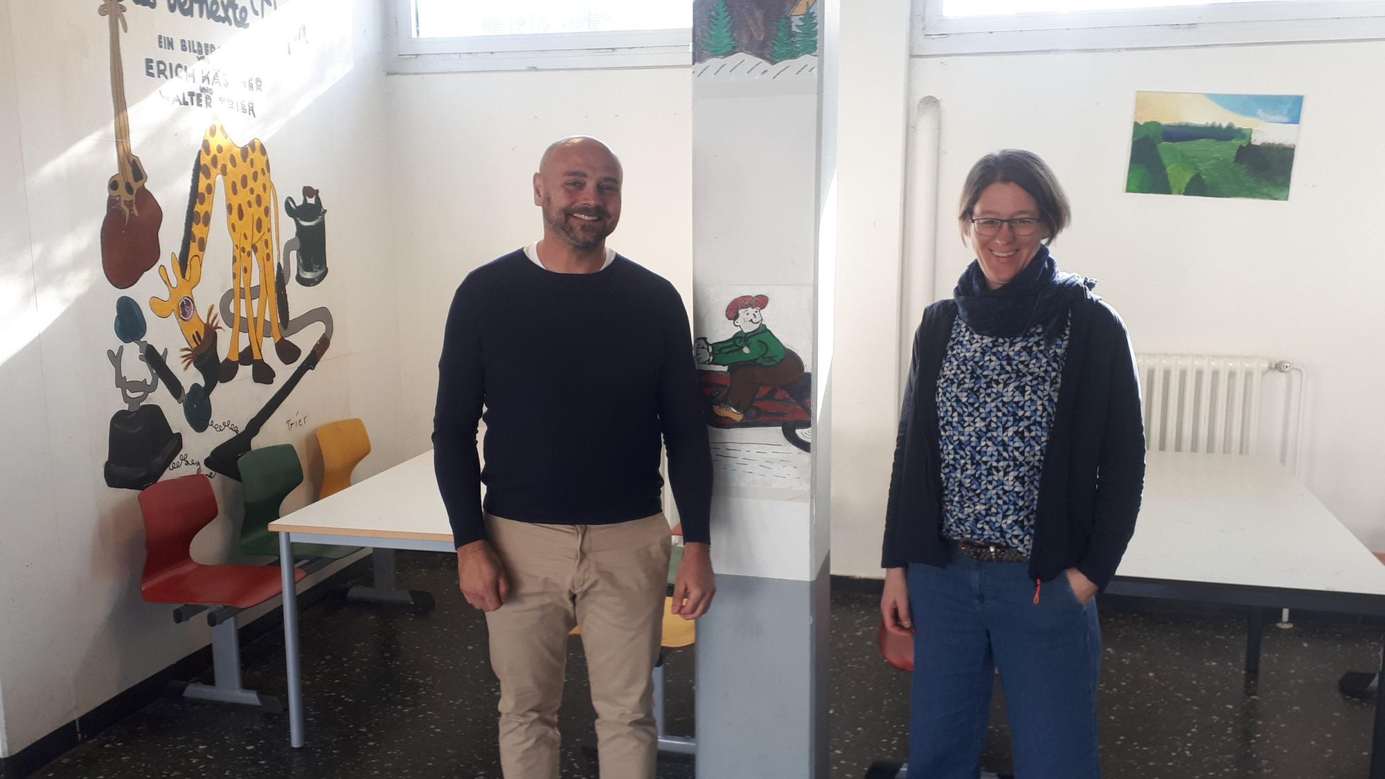Ein Mann und eine Frau stehen in einem Schulfoyer