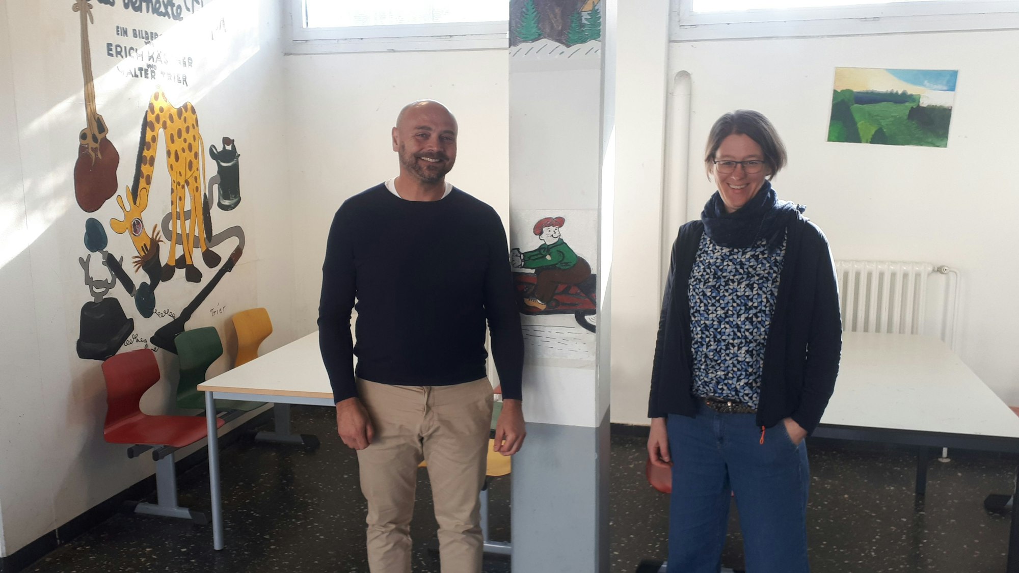 Ein Mann und eine Frau stehen in einem Schulfoyer