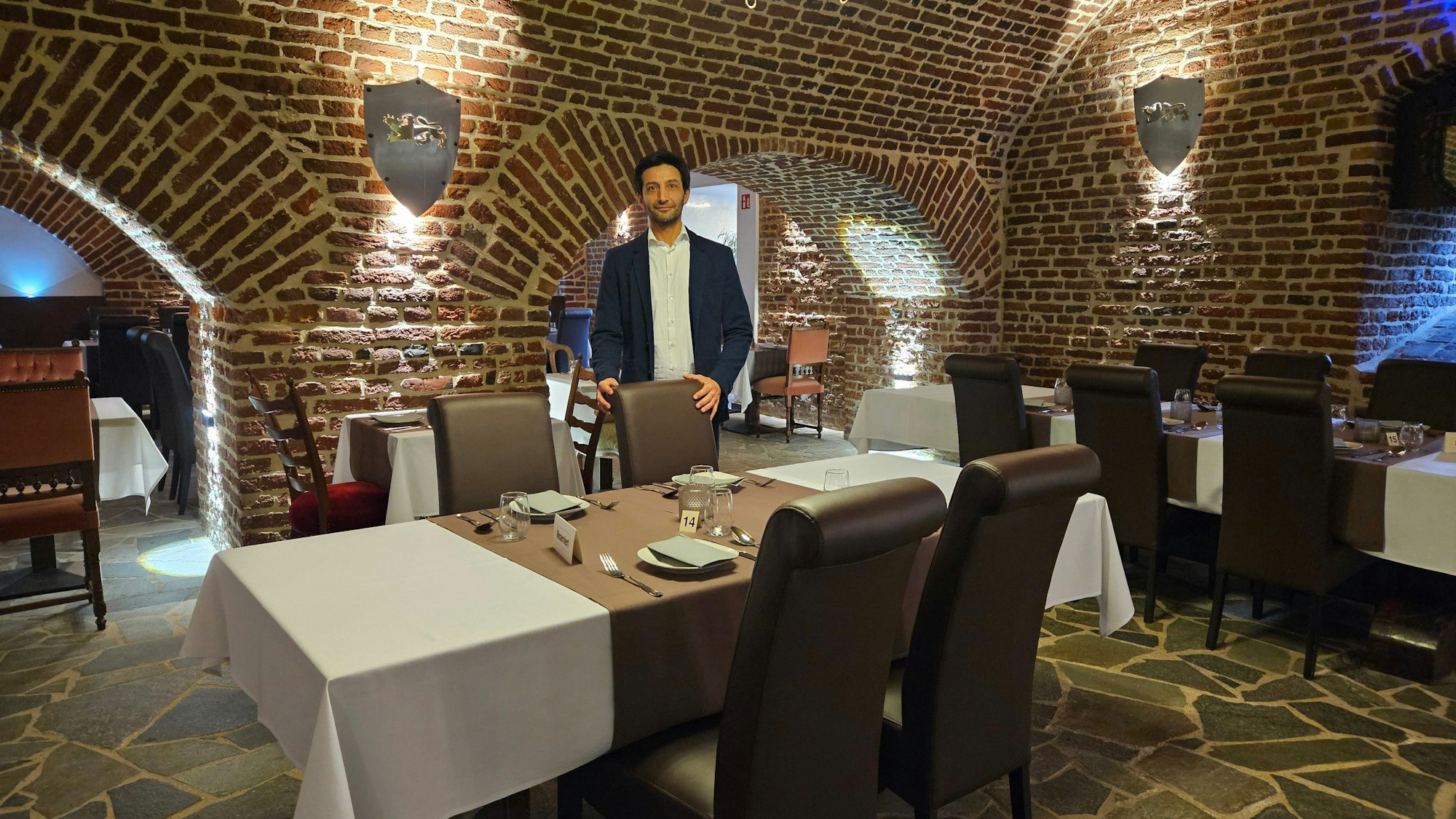 Ein Mann steht an einem gedeckten Tisch in einem Restaurant.