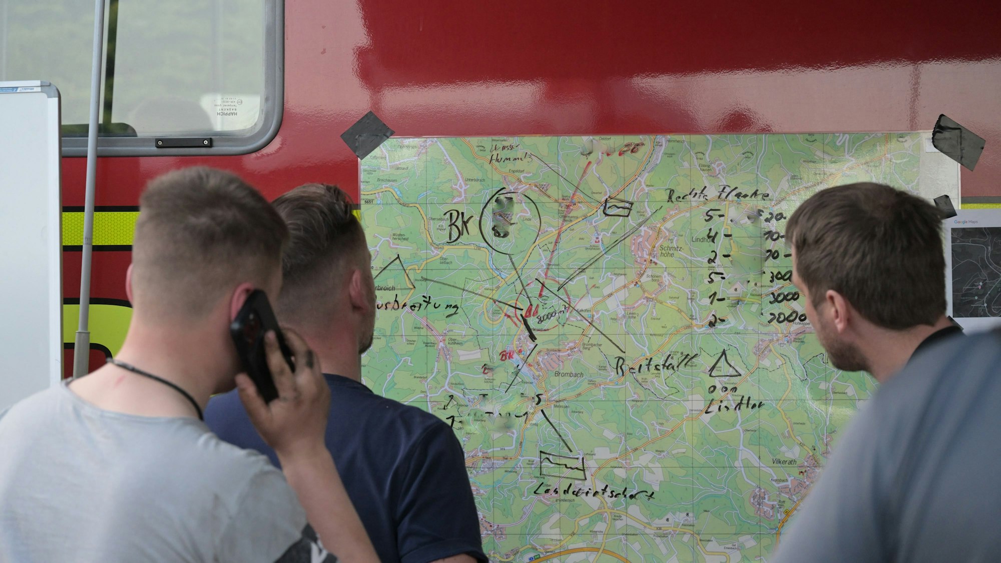 Die Einsatzleitung steht bei der Besprechung vor einer Karte.