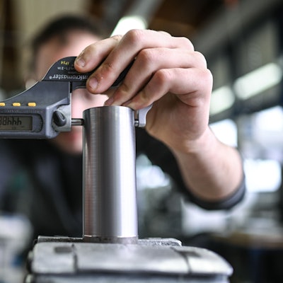 Ein Auszubildender im Metall-Handwerk misst in einem Ausbildungszentrum den Durchmesser eines Werkstücks.