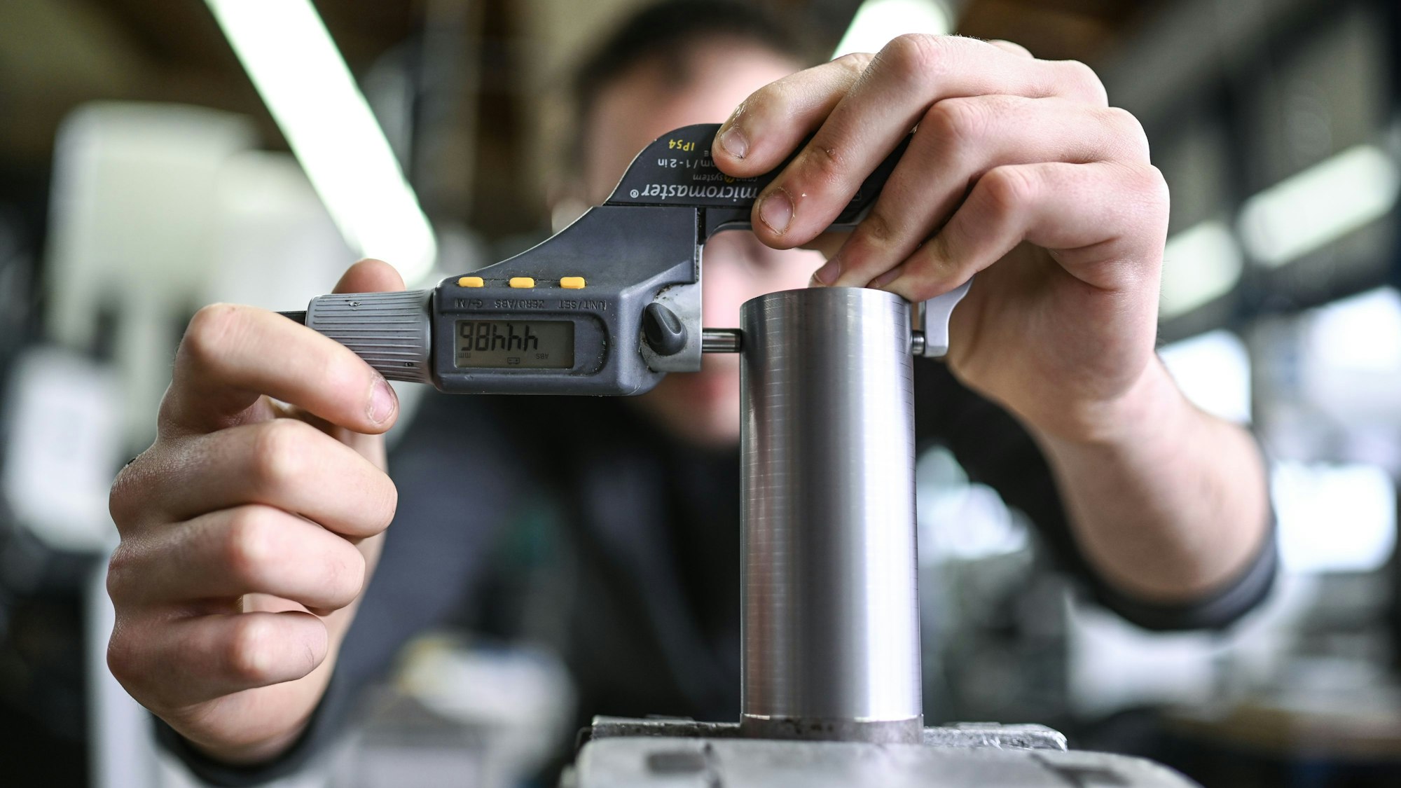 Ein Auszubildender im Metall-Handwerk misst in einem Ausbildungszentrum den Durchmesser eines Werkstücks.