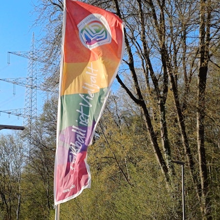 Auf einer Flagge des Fußball-Verbands Mittelrhein im Regenbogenmuster steht „Fußball ist Vielfalt“.
