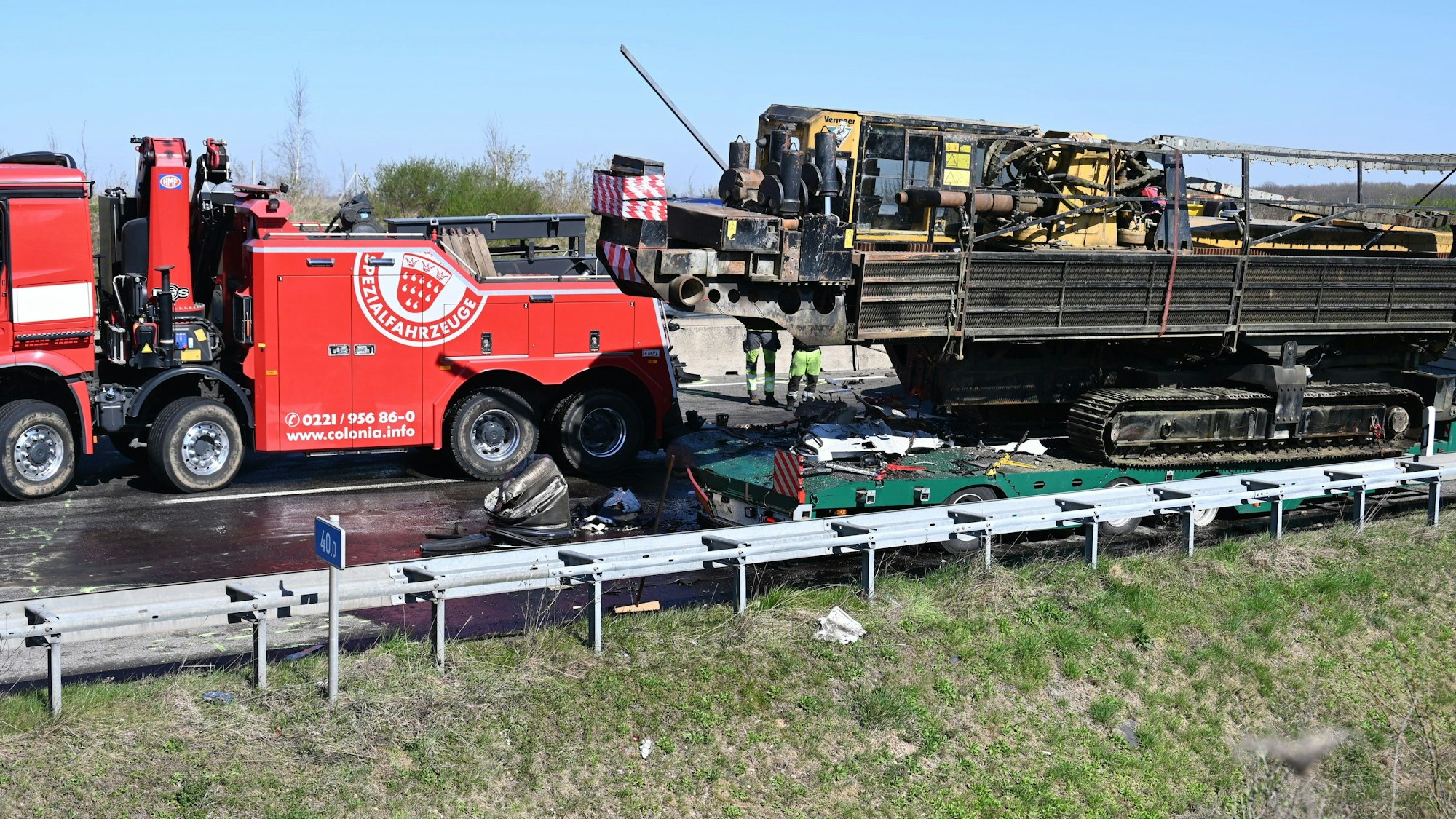 Das Bild zeigt ein Bergungsfahrzeug und einen ausgebrannten Lkw-Auflieger.