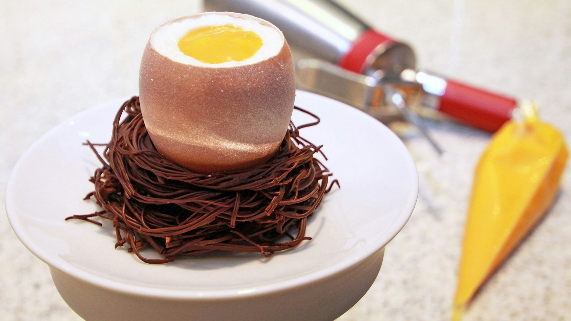 Ein geöffnetes Osterei auf einem Nougat-Osternest.