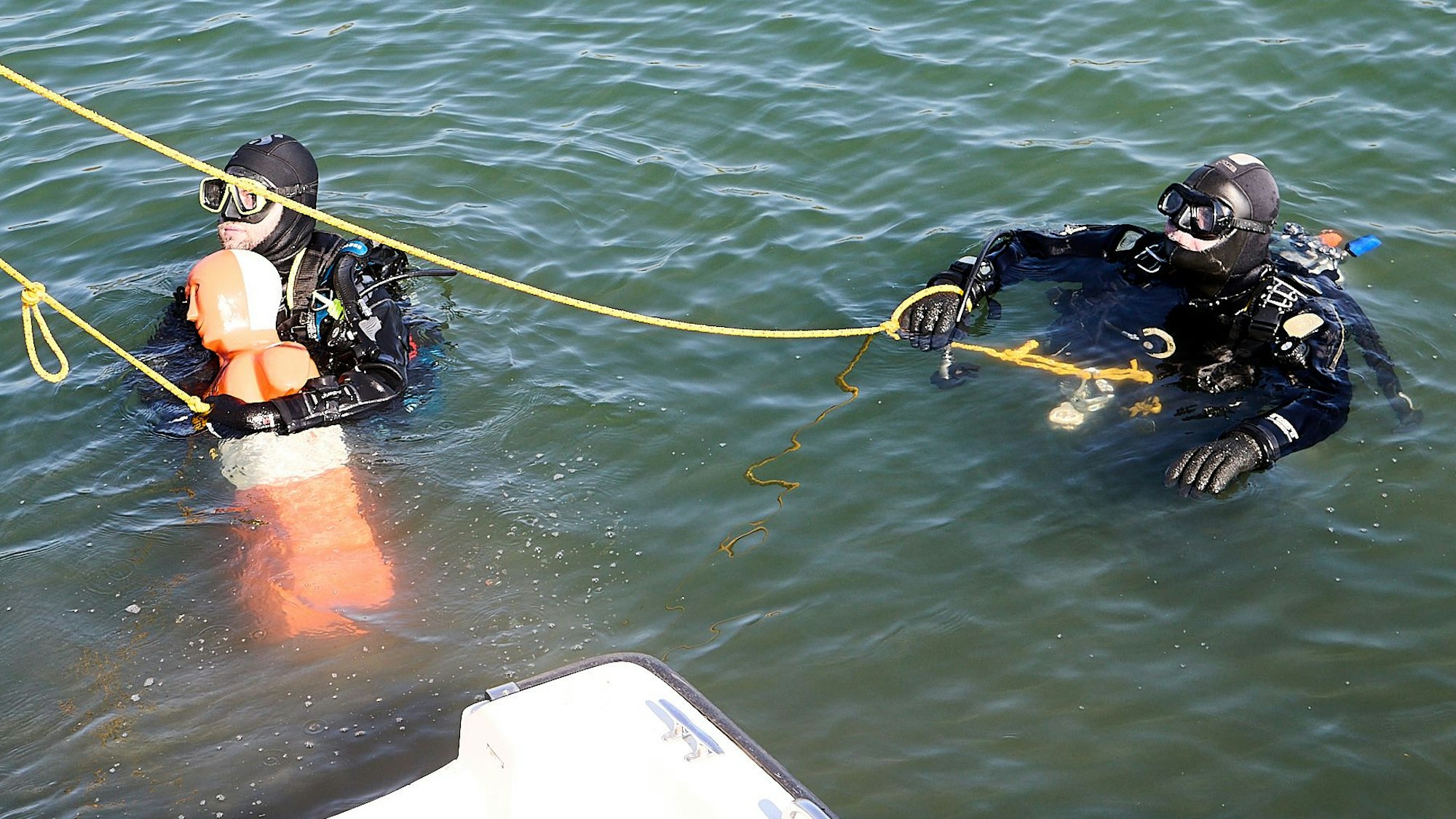 Das Bild zeigt zwei Taucher. Einer von ihnen hat eine Puppe sichernd umarmt.