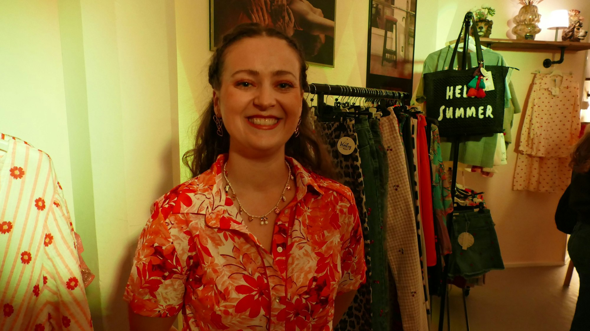 Eine Frau in einem orange-gelben Sommerkleid lächelt.