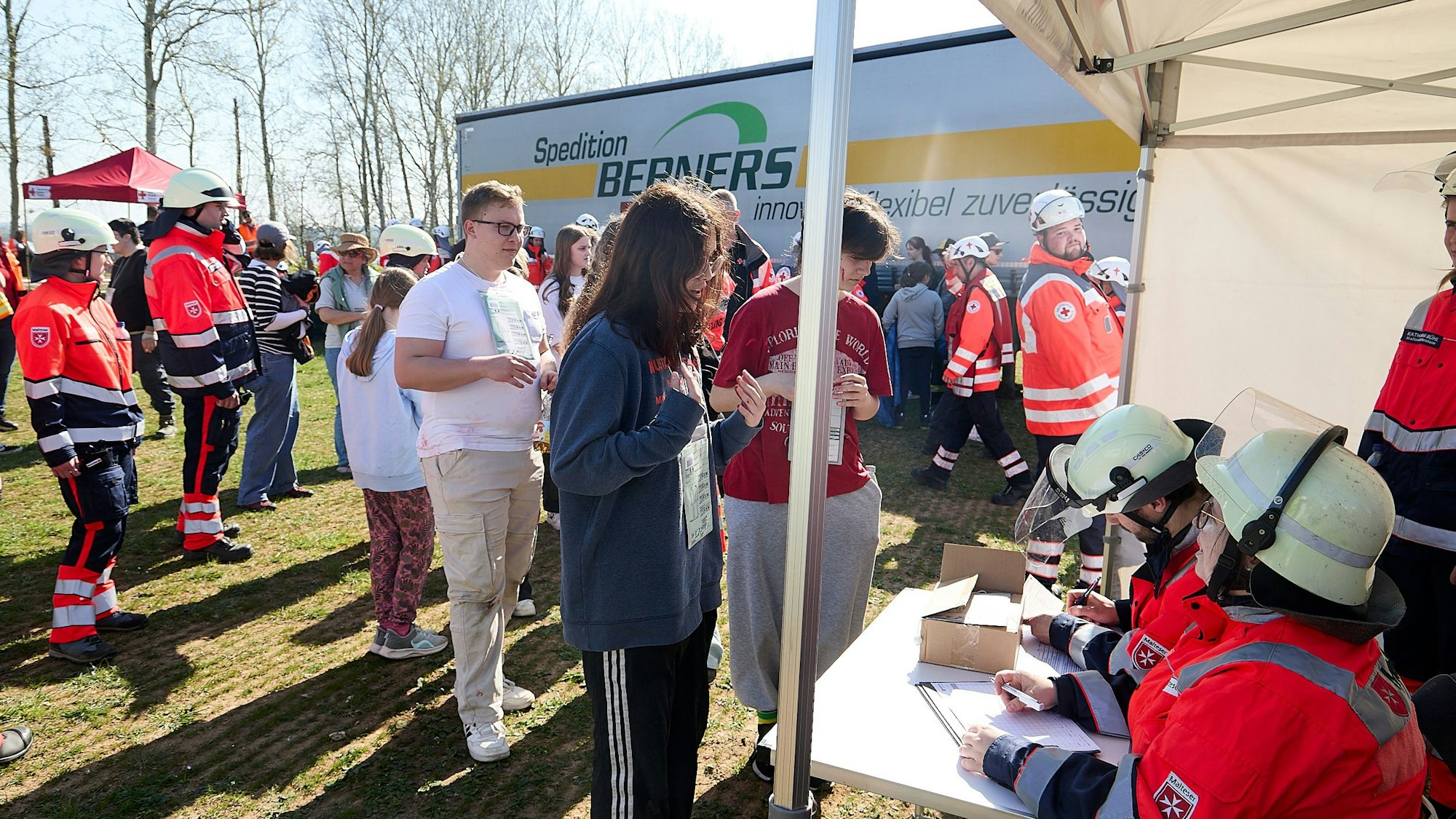 Das Bild zeigt einige der für die Übung engagierten Darsteller, die sich vor einer Registrierungsstelle aufgereiht haben.