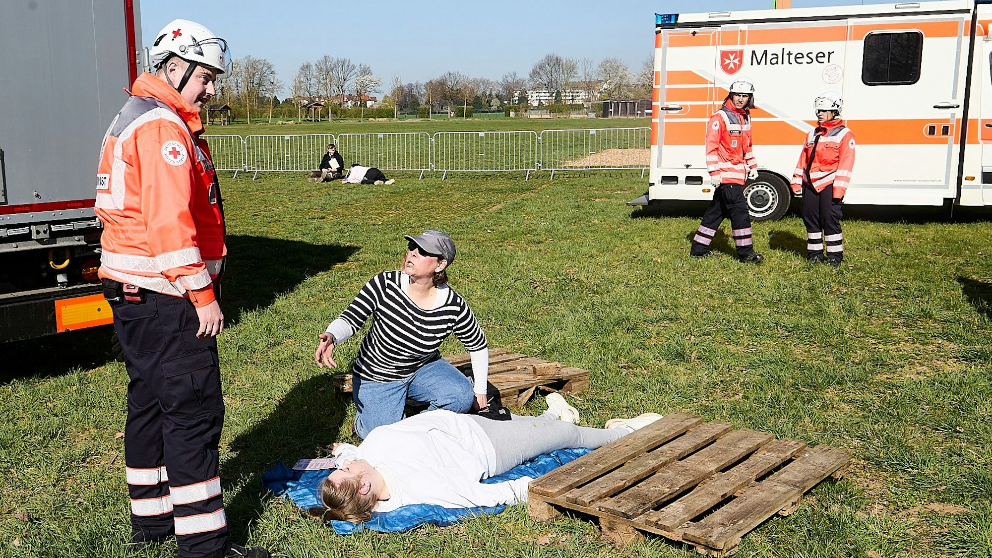 Das Bild zeigte eine Frau mit Kappe, die neben einer Verletzten kniet und gestikulierend auf einen Rettungsassistenten einredet.