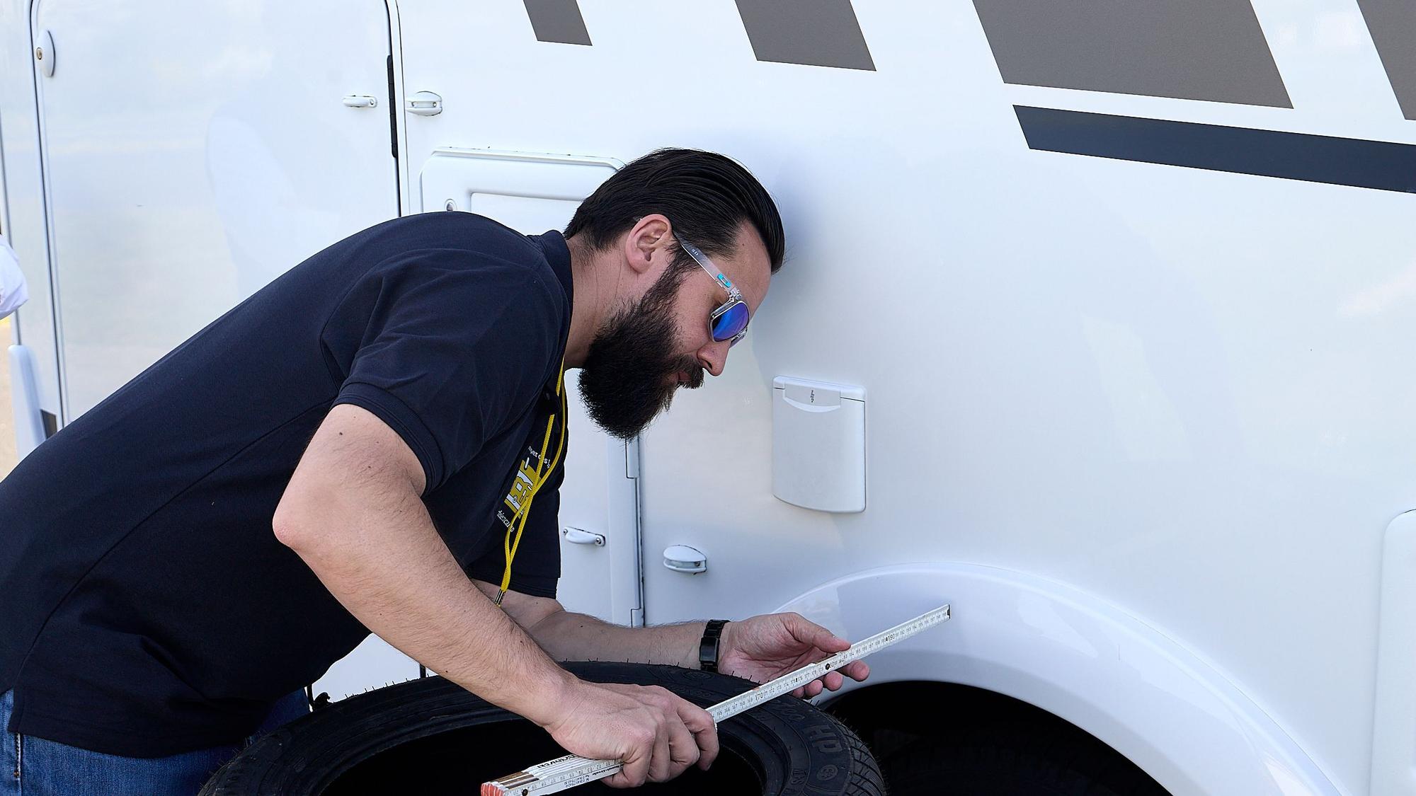 Ein Mann hält einen Zollstock an den Camper.