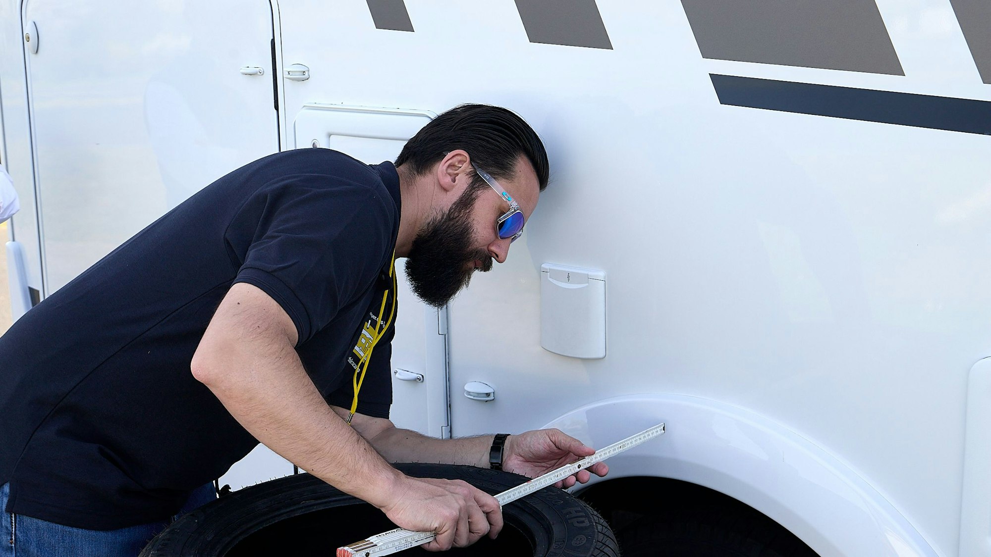 Ein Mann hält einen Zollstock an den Camper.