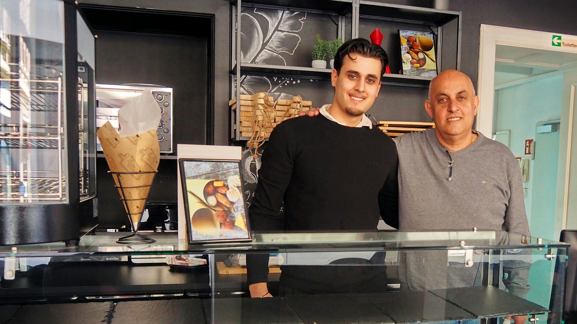 Ein Vater und sein Sohn stehen hinter der Theke ihres Restaurants.