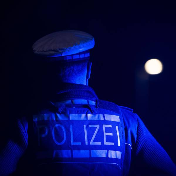 Ein Polizist steht neben einem Polizeifahrzeug (gestellte Szene).