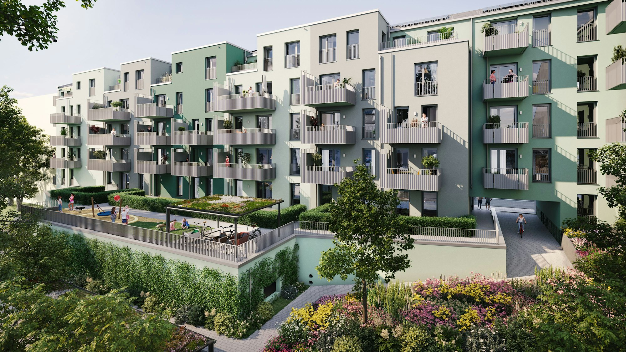 Mehrere Häuser mit Balkonen sind über einen grünen Innenhof mit Spielplätzen und Bepflanzungen aus zu sehen.