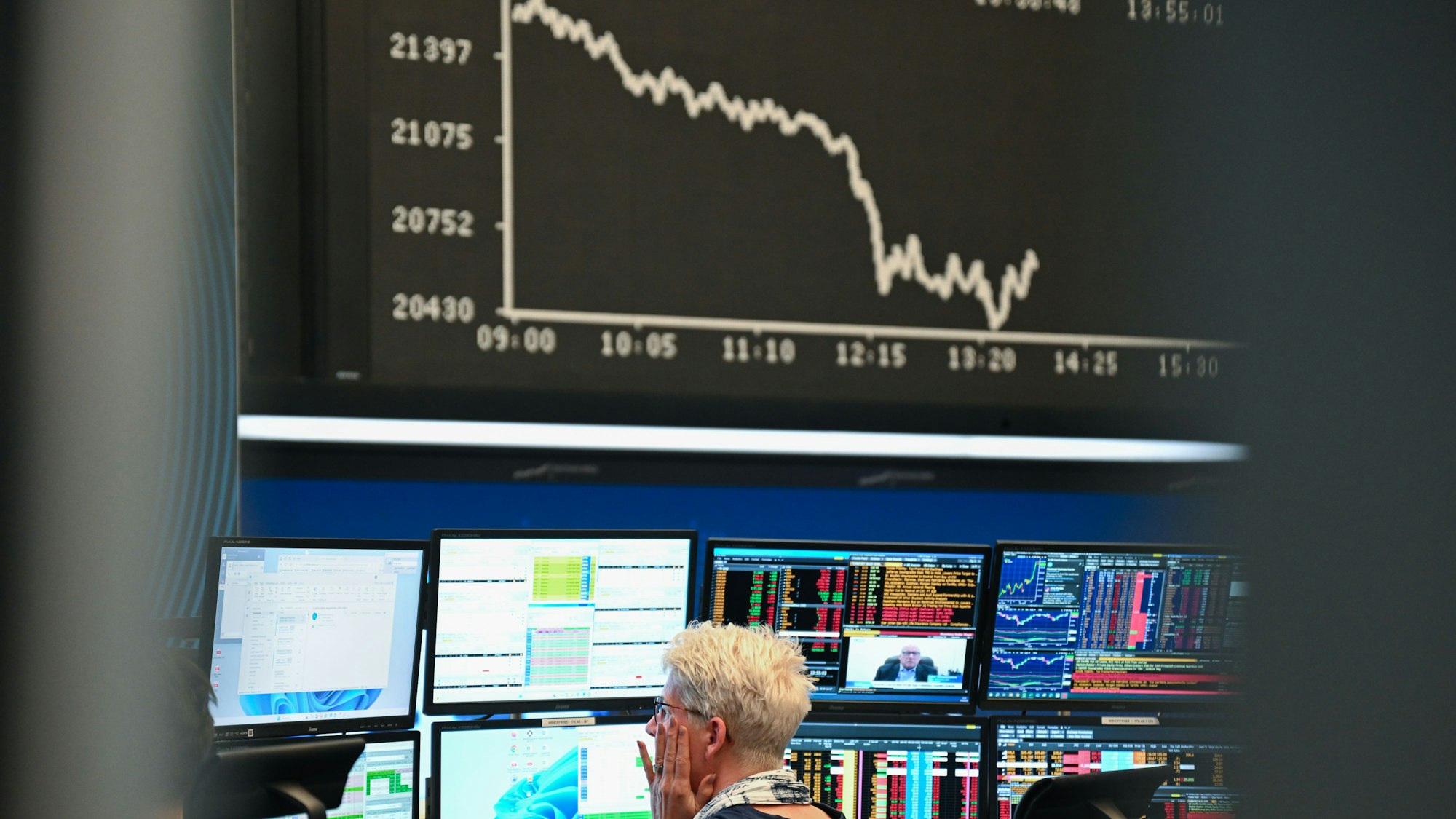 Eine Börsenhändlerin beobachtet auf dem Parkett der Frankfurter Wertpapierbörse ihre Monitore, während die Anzeigetafel mit der Dax-Kurve fallende Kurse anzeigt. US-Präsident Donald Trump hatte ein gewaltiges Zollpaket gegen Handelspartner in aller Welt erlassen.