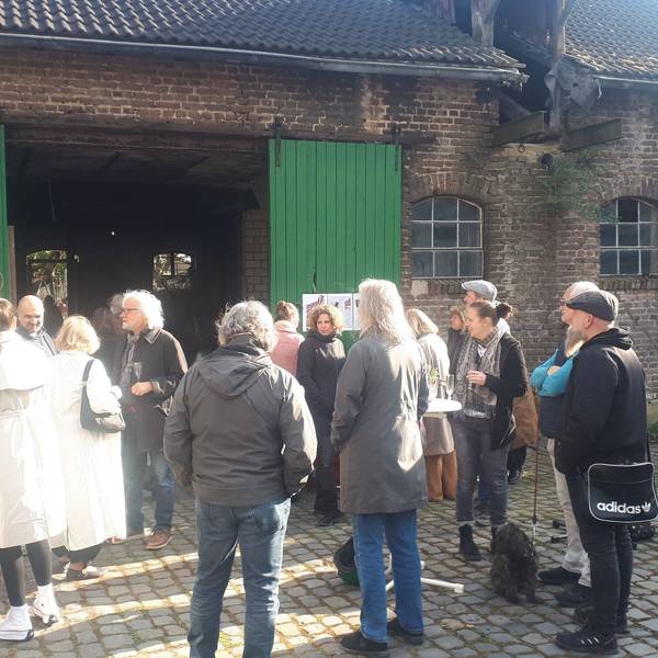 Eine Gruppe Menschen steht vor einem Hofgebäude mit großen grünen Holztüren.