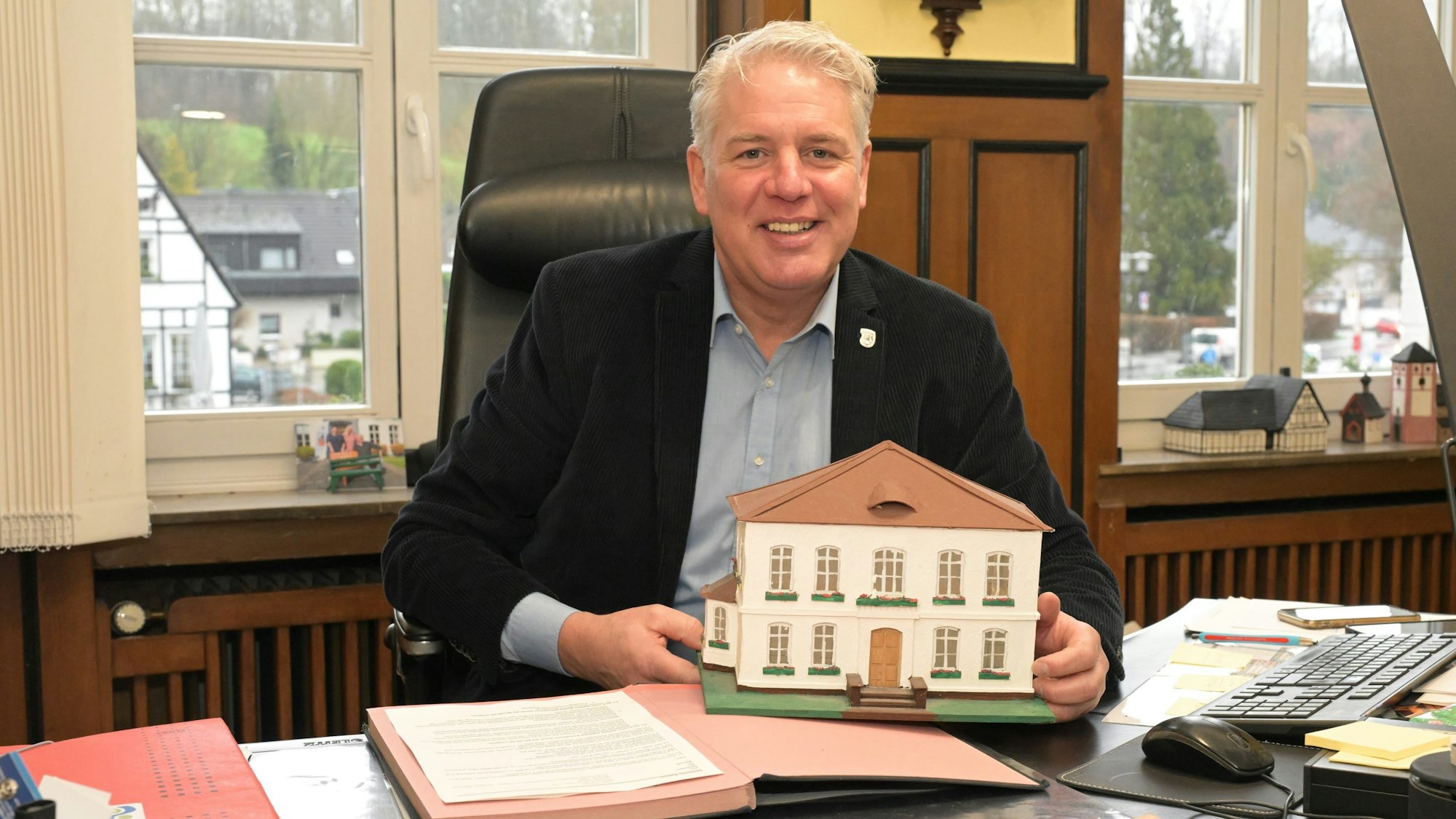 Bürgermeister Robert Lennerts in seinem Dienstzimmer. Er hält ein Modell des Rathauses in der Hand.