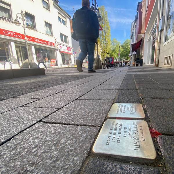 Zu sehen sind zwei Stolpersteine, die in einem Gehwegpflaster eingelassen sind.