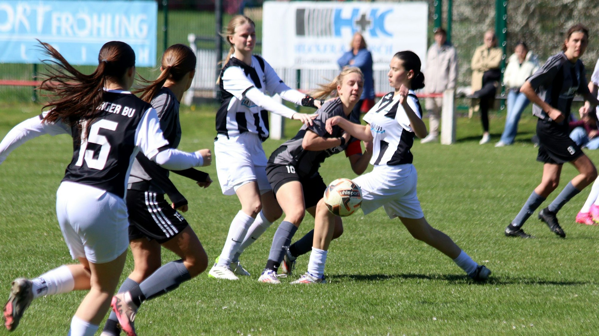 Eine Fußballerin wird beim Kampf um den Ball von hinten und vorne von Gegenspielerinnen attackiert.