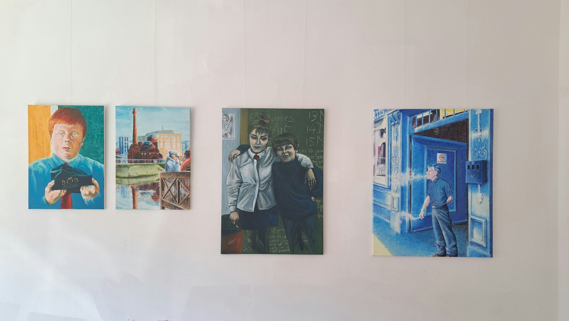 Vier Bilder, die teils Menschen, teils Industriegebäude zeigen, hängen nebeneinander.