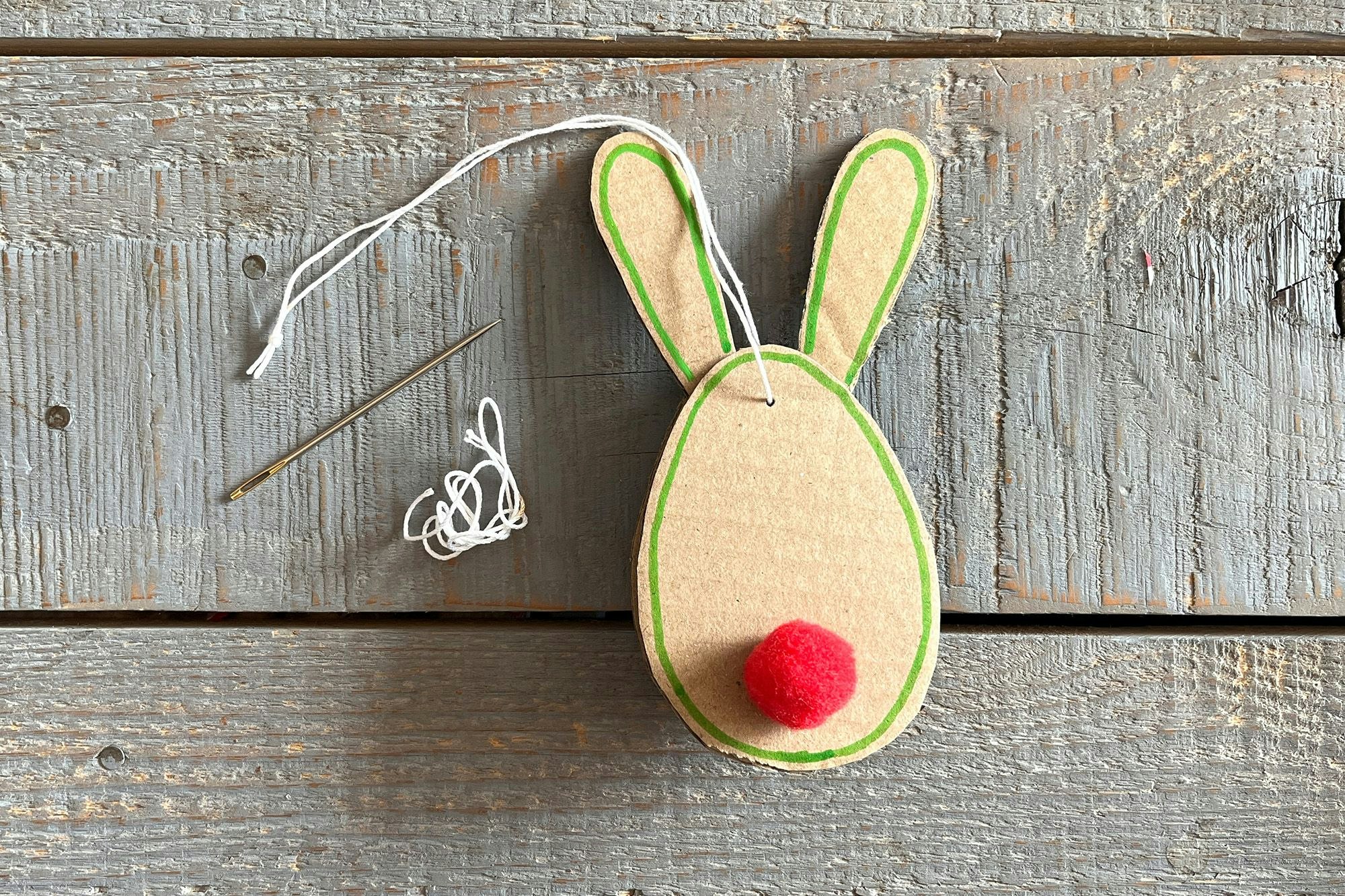 Bunte Bommel befestigen, mit einem Stift die Konturen umfahren und am Ende mit der Nadel einen Faden zum Aufhängen befestigen.