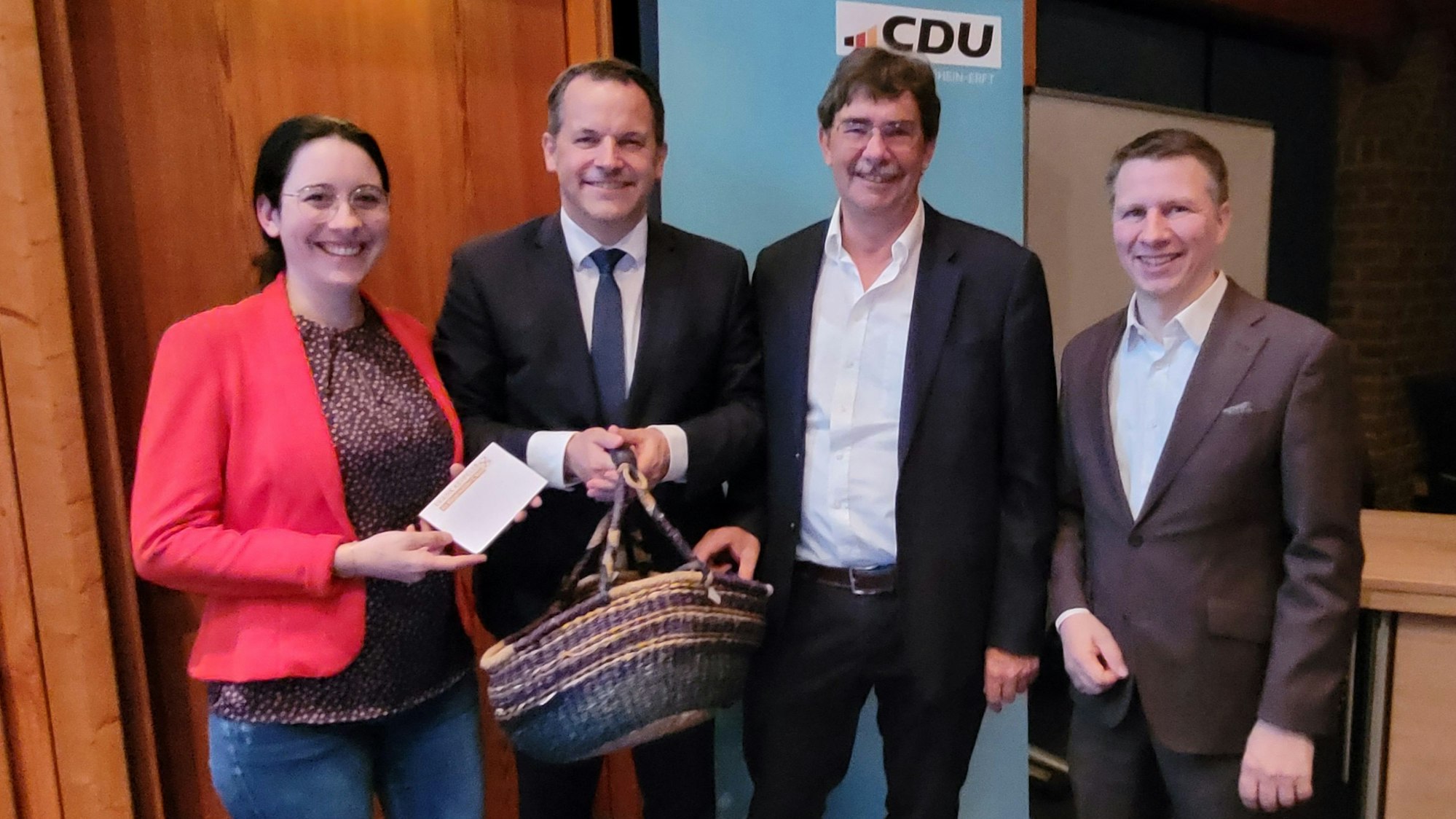 Eine Frau und drei Männer vor einem CDU-Transparent.