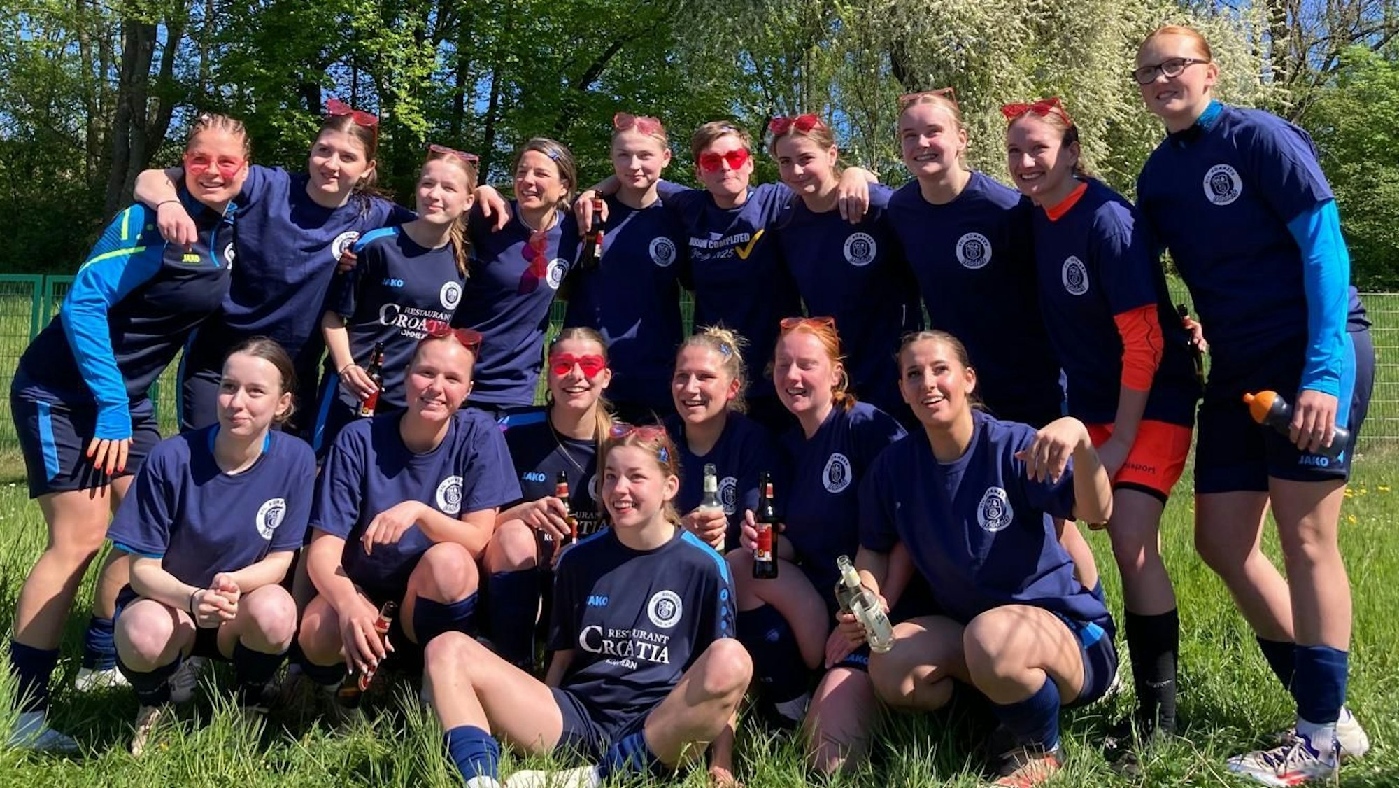 Die Spielerinnen des VfL Kommern freuen sich über den Aufstieg und tragen rosarote Herzchen-Brillen.