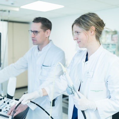 Auf dem Bild sind eine Ärztin und ein Arzt zu sehen, die gemeinsam an einem medizinischen Gerät arbeiten.