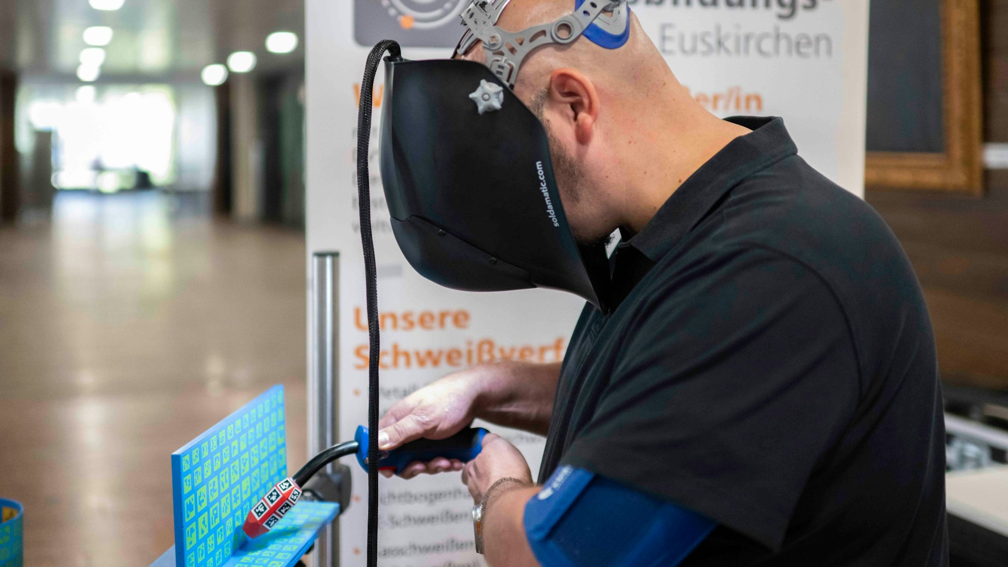 Ein Mann übt mithilfe eines Simulators das Schweißen. Funken sprühen dabei nur am Monitor.