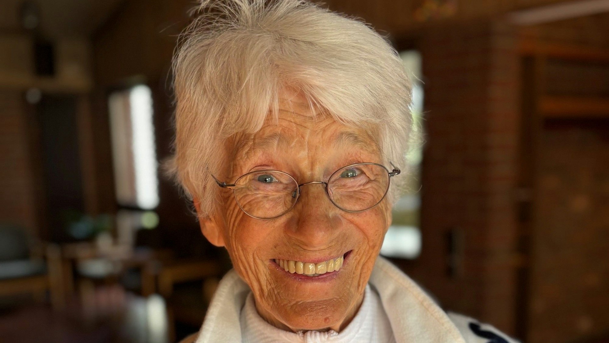 Eine Frau mit grauer Kurzhaarfrisur lächelt.