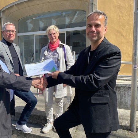 Zu sehen sind drei Mitglieder des Vereins Bovivo, die Ralf Ritter die gesammelten Unterschriften überreichen.