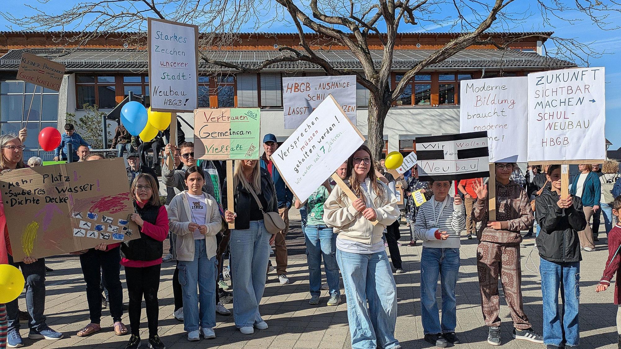 Schüler und Eltern halten auf dem Schulhof Protestplakate hoch.