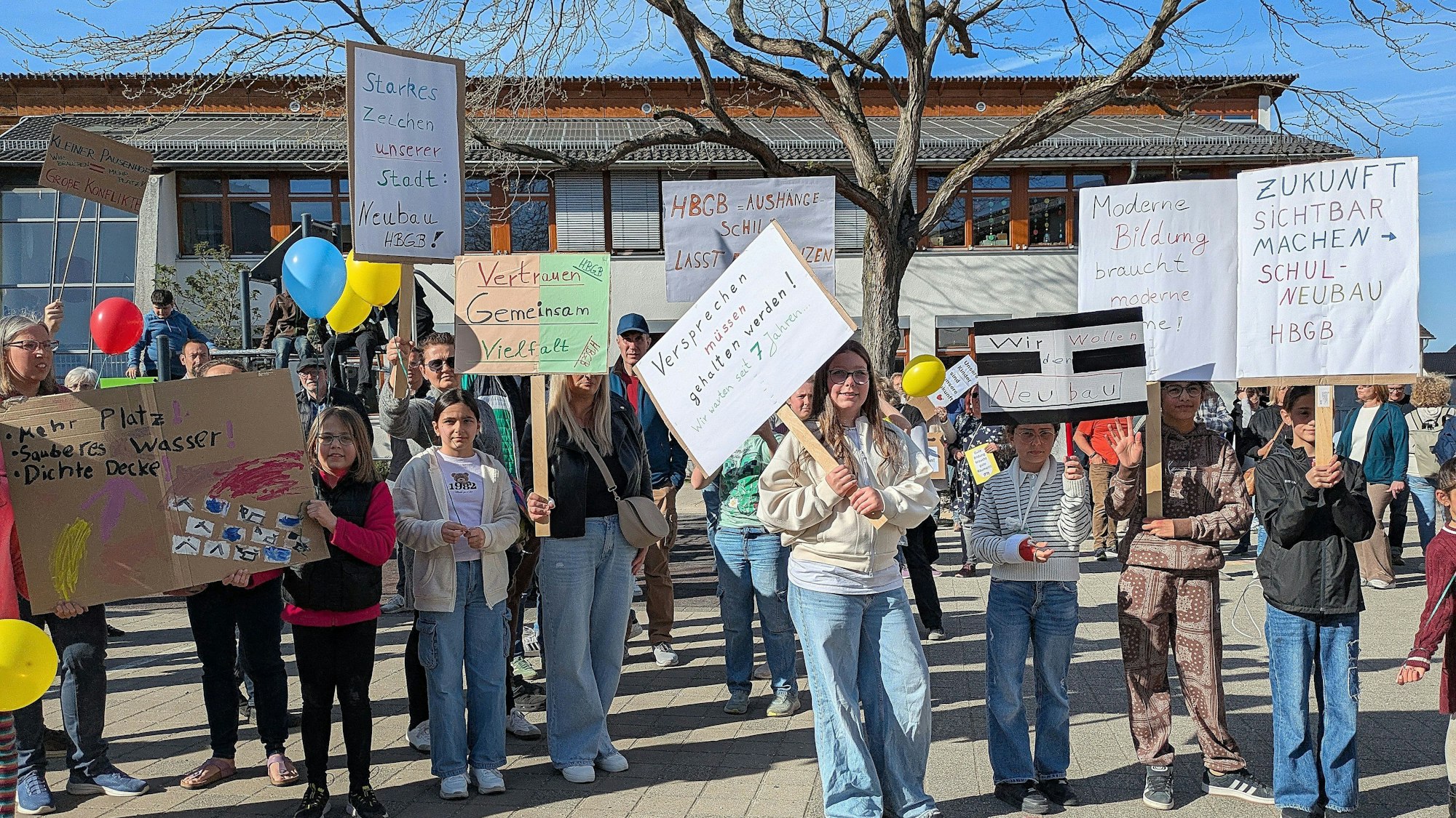 Schüler und Eltern halten auf dem Schulhof Protestplakate hoch.