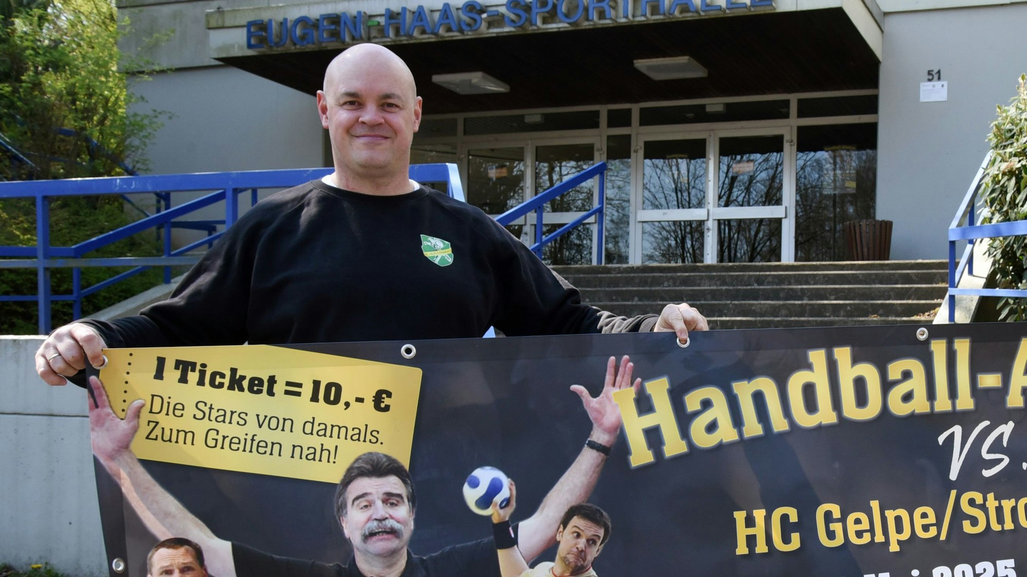 Zu sehen ist ein Handballer mit einem Plakat.