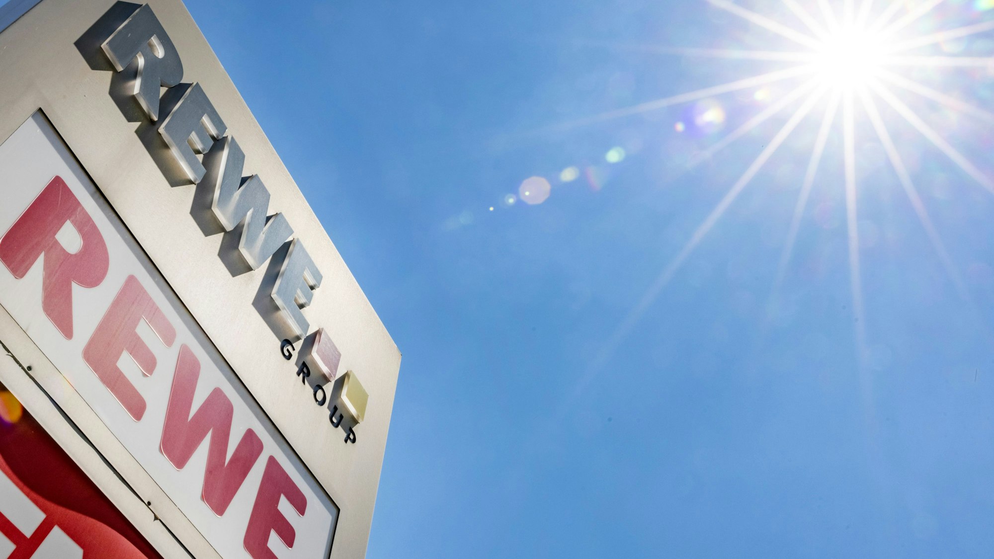 Firmenschild der Rewe Group steht vor der Firmenzentrale in Köln.