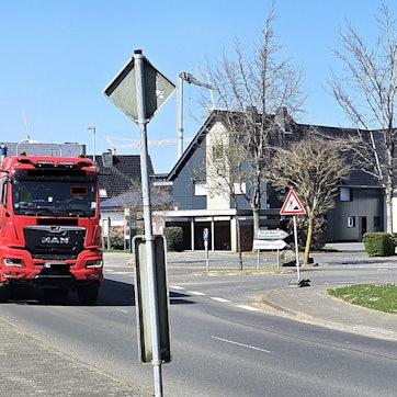 Ein Lastwagen mit Auflieger fährt nahe an Häusern in Schöneseiffen vorbei.