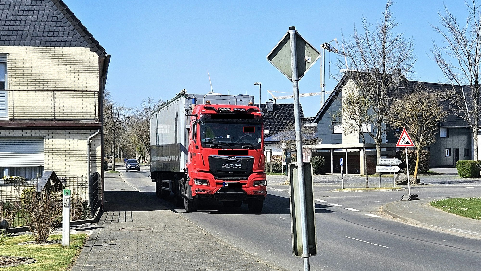 Ein Lastwagen mit Auflieger fährt nahe an Häusern in Schöneseiffen vorbei.