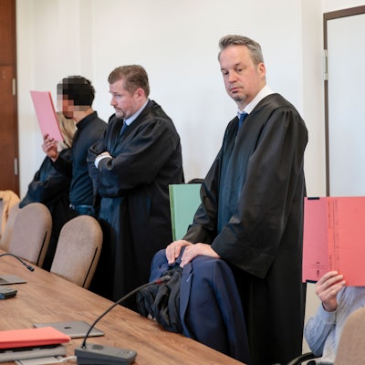 Die drei Angeklagten mit ihren Anwälten beim Prozessauftakt.